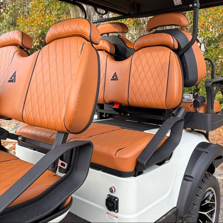 Brown leather seats on a golf cart with a white frame, surrounded by trees.